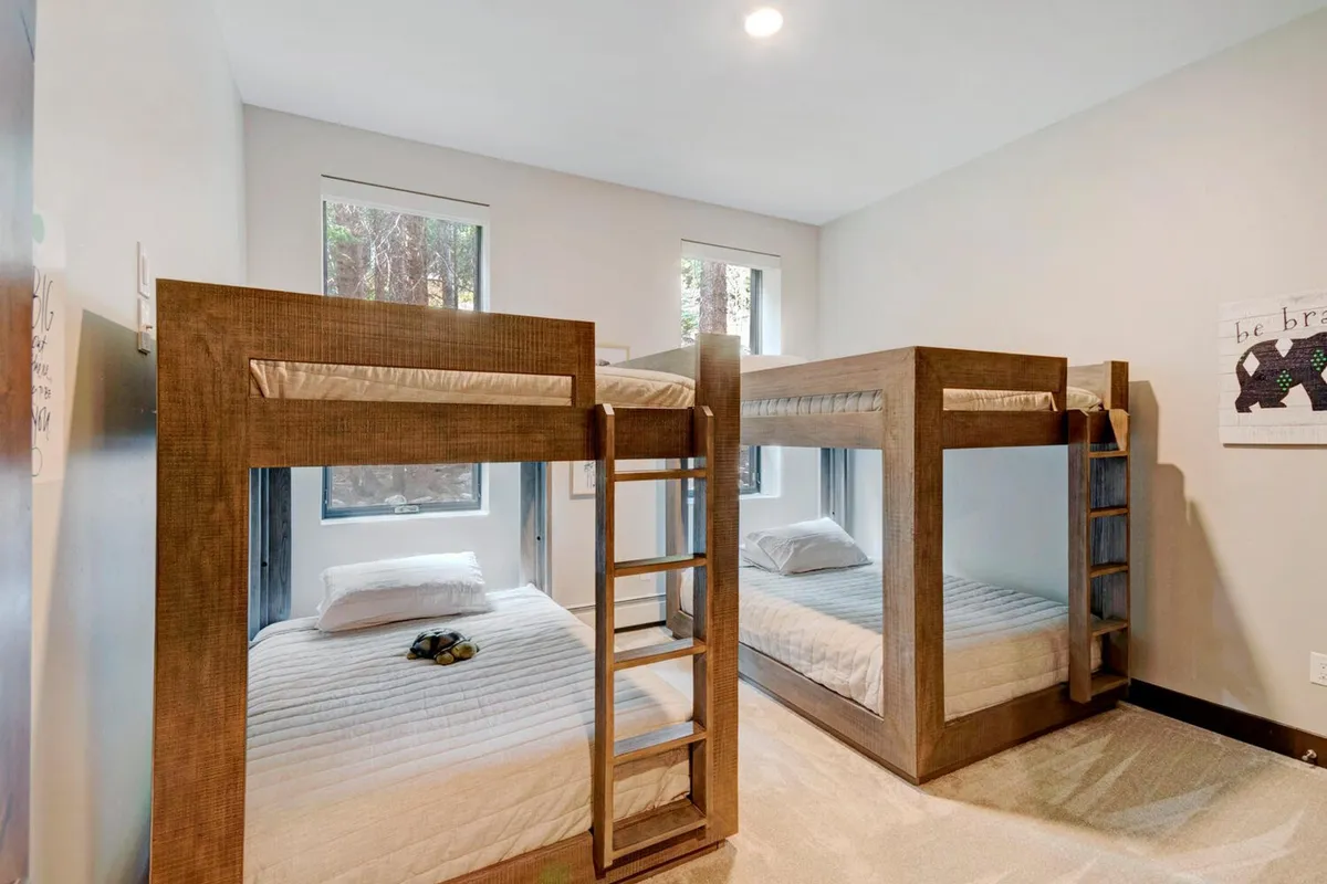 A playful, inviting bedroom with cozy bunk beds and natural light flooding in from the windows. The space is designed for both sleeping and play, making it ideal for children or multi-generational groups.