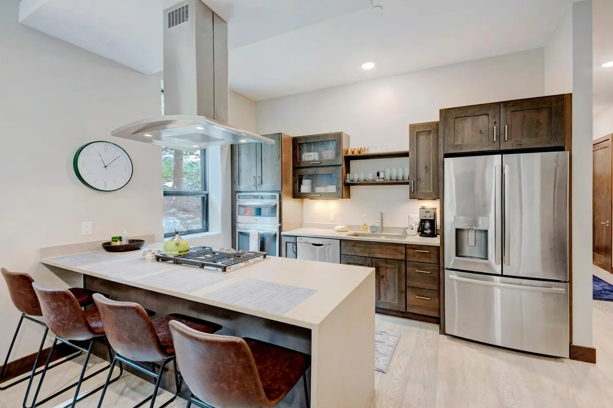 A bright, modern kitchen with a spacious island, stainless steel appliances, and large windows letting in abundant natural light. The kitchen is perfectly equipped for cooking and entertaining, with ample prep space and seating for casual gatherings.