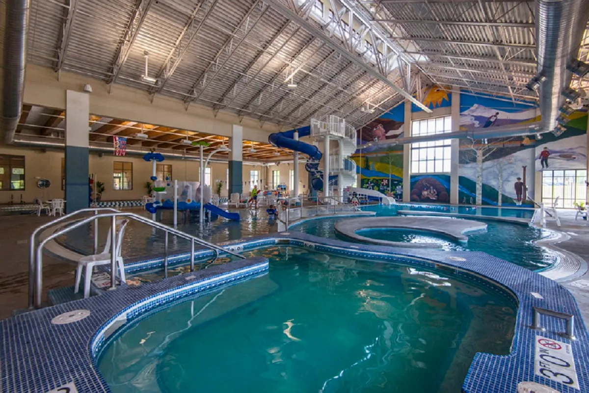 An energetic indoor waterpark scene with children playing, colorful water slides, and cheerful murals. The atmosphere is playful, with families enjoying various aquatic activities together.